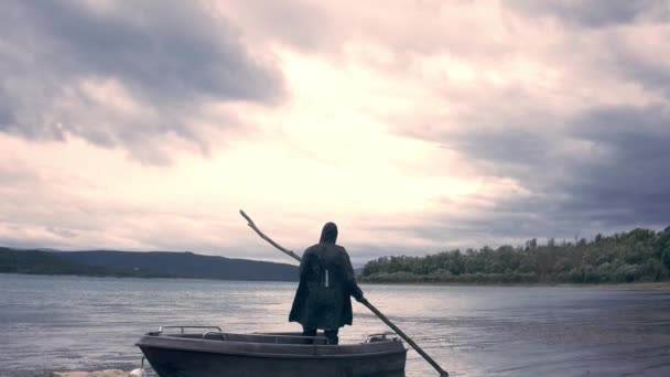 Одинокий силуэт рыбака, стоящего на лодке на берегу озера персонал холдинга глядя на облака дождя Конец времен изменения климата Загадка беспомощности — стоковое видео