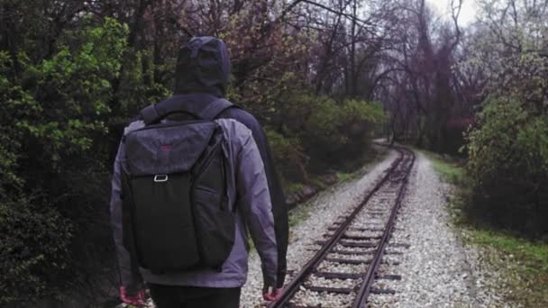 Lonely Hooded Man Walking Railroad op een regenachtige dag Eenzaamheid Backpacken Slow Motion 4 K Raw — Stockvideo