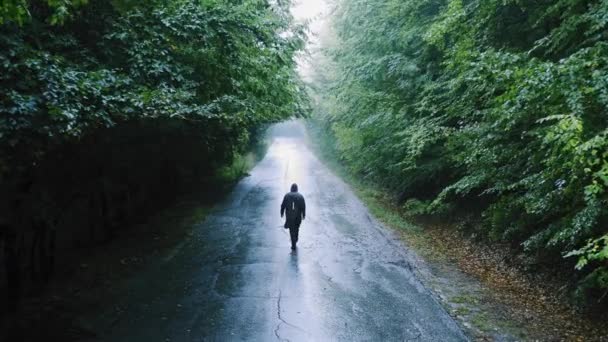 Einsamer Mann mit Kapuze, der am regnerischen Tag dem Licht entgegen geht Einsamkeit Reisen Slow Motion Drone — Stockvideo