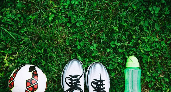 Sports shoes sneakers, ball and bottle of water on a fresh green grass — Stock Photo, Image