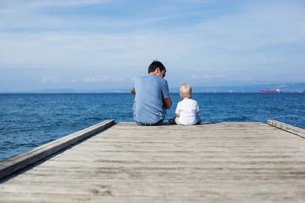 Far med son sitter på havet piren — Stockfoto