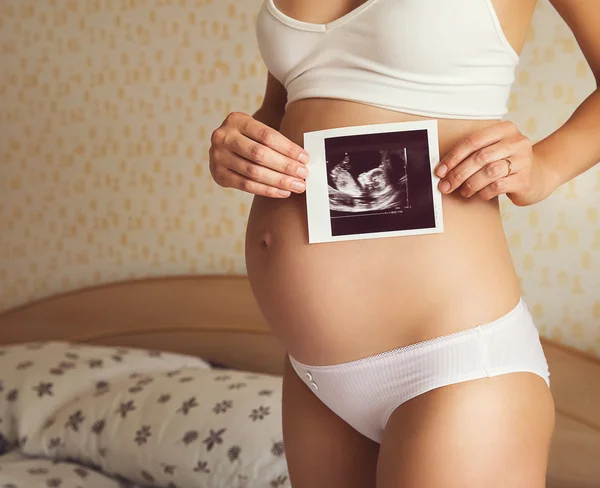 Femme enceinte tenant une image échographique — Photo