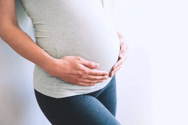 Close-up zwangere vrouw op een witte achtergrond. — Stockfoto