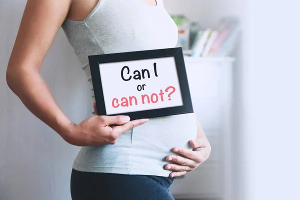 Mujer embarazada sostiene pizarra con mensaje de texto - ¿Puedo o no puedo ? — Foto de Stock