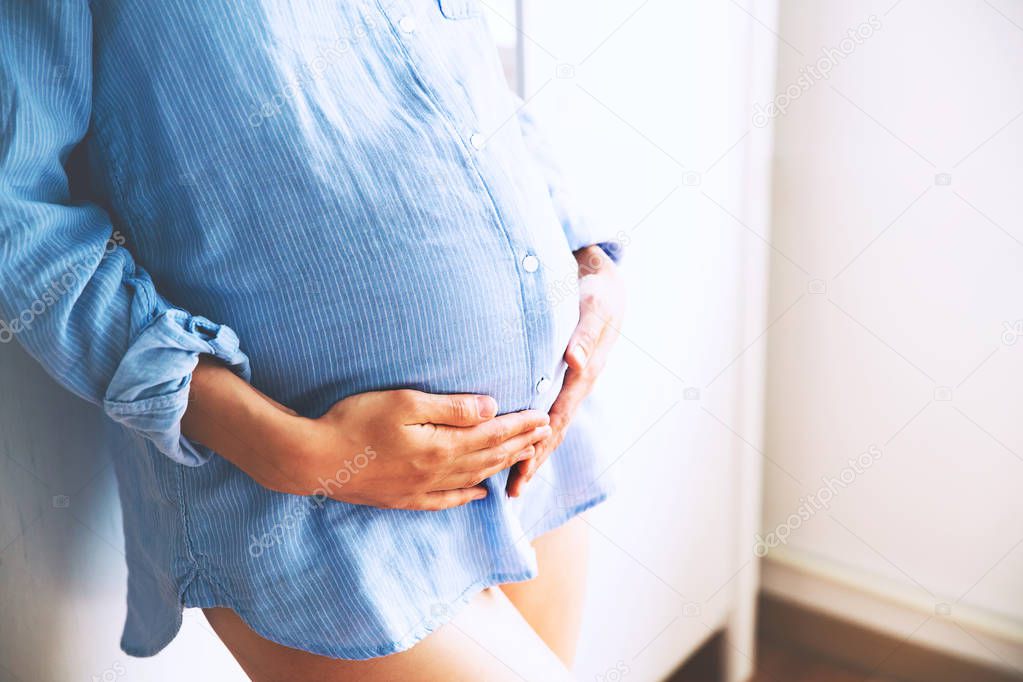Close-up pregnant woman at home interiors.