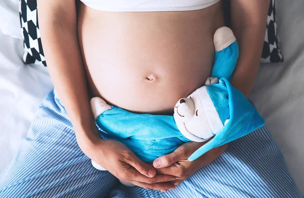 Close-up barriga da mulher grávida com ursinho de pelúcia . — Fotografia de Stock