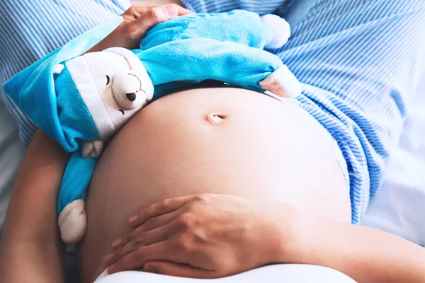 Primo piano pancia di donna incinta con orsacchiotto giocattolo . — Foto Stock