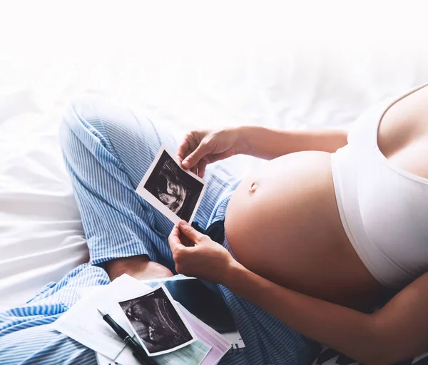 Mujer embarazada toma notas en el cuaderno y la celebración de ultrasonido im —  Fotos de Stock