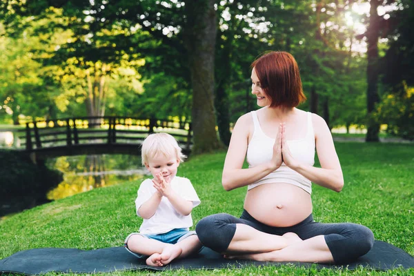 Mujer embarazada, madre con hijo en posición de loto . — Foto de Stock