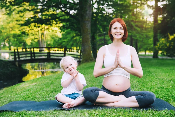 Těhotná žena, matka se synem v lotosové pozici. — Stock fotografie