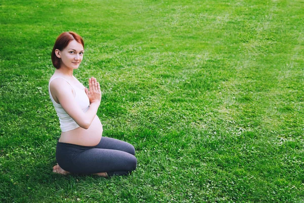 Krásná těhotná žena dělá prenatální jóga na přírodní venku. — Stock fotografie