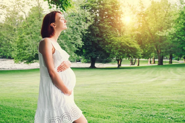 Mooie zwangere vrouw in witte jurk op aard. — Stockfoto