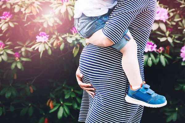 Femme enceinte avec enfant sur fond nature, gros plan . — Photo