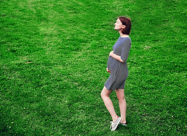Красивая беременная женщина в платье на природе. — стоковое фото