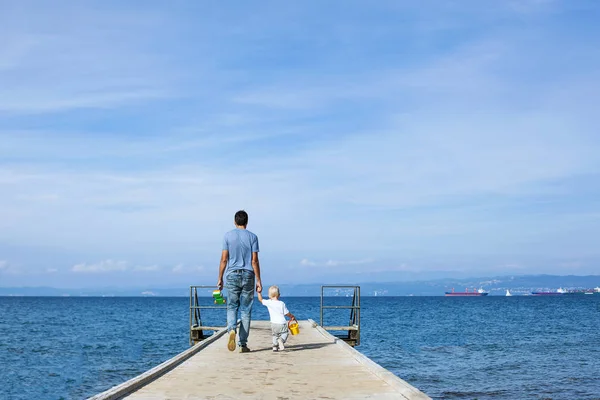 Padre con hijo caminando en el muelle del mar . — Foto de Stock