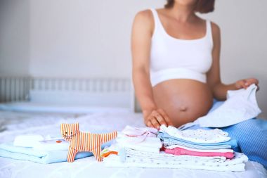 Bebek giysileri, malzeme ve ev iç hamile kadında yığını