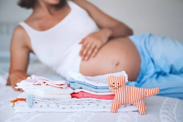 Купа дитячого одягу, речей і вагітної жінки в домашньому інтер'єрі — стокове фото