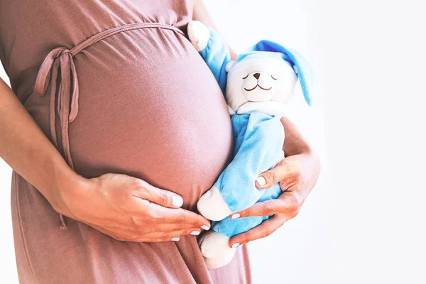 Närbild gravid kvinnas mage med leksak nallebjörn. — Stockfoto