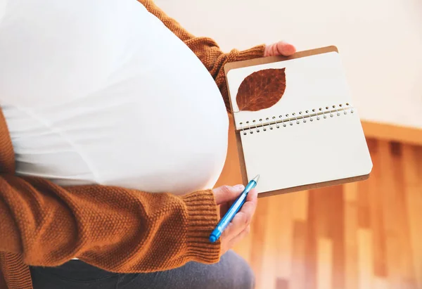 Mulher grávida faz anotações no caderno . — Fotografia de Stock