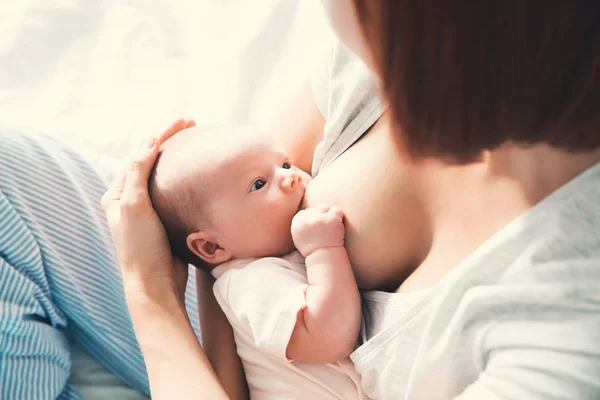 Mãe amamentando bebê recém-nascido em casa . — Fotografia de Stock
