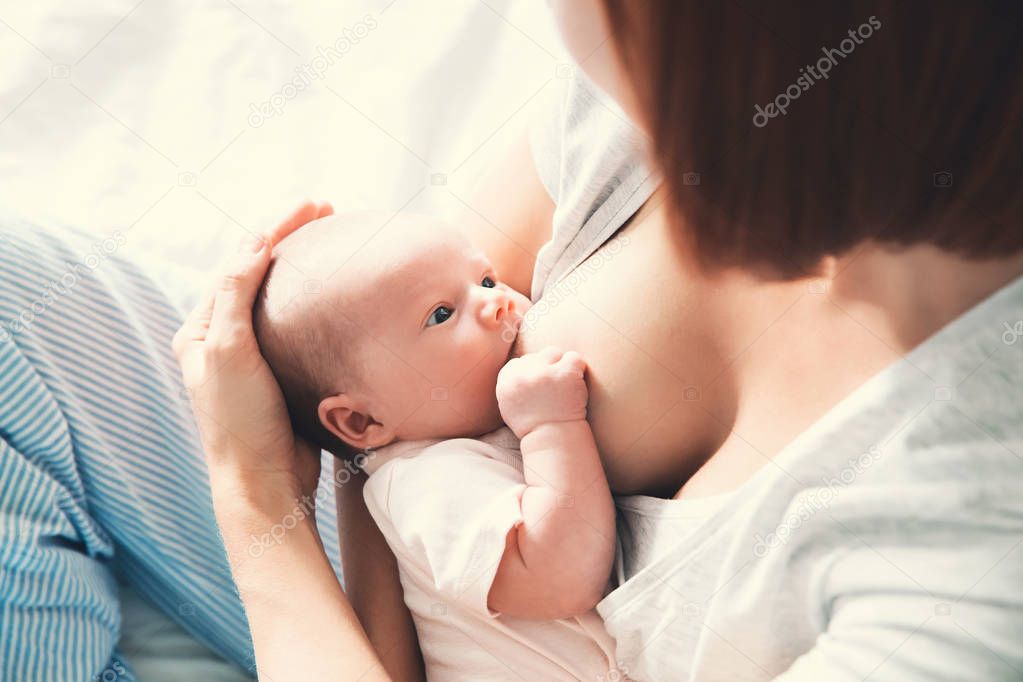 Mother breastfeeding newborn baby at home. 