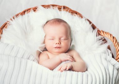 Bir şal üzerinde beyaz battaniye içinde yeni doğmuş bebek uyku.