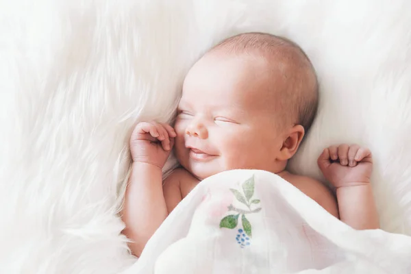 Bebé recién nacido sonriente dormido envuelto en una manta blanca . — Foto de Stock