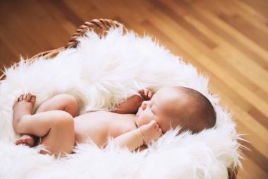 Bir şal üzerinde beyaz battaniye içinde yeni doğmuş bebek uyku.