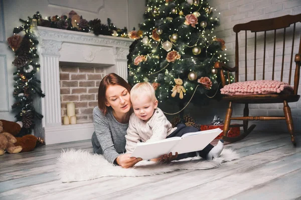 Мать с ребенком среди рождественских украшений чтение истории в — стоковое фото