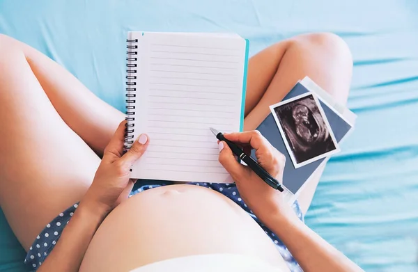 Donna incinta prende appunti nel taccuino e tenendo gli ultrasuoni im — Foto Stock