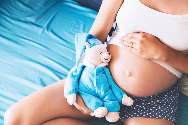 Närbild gravid kvinnas mage med leksak nallebjörn. — Stockfoto