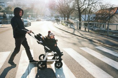 Baba ve çocuk çocuk arabasındaki bebek bir yol çapraz. 