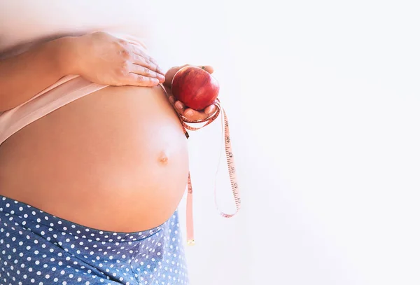 Close up de uma mulher grávida segurando maçã e fita métrica . — Fotografia de Stock