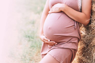 Hamile kadını karnından doğa arka plan üzerinde ellerini tutar