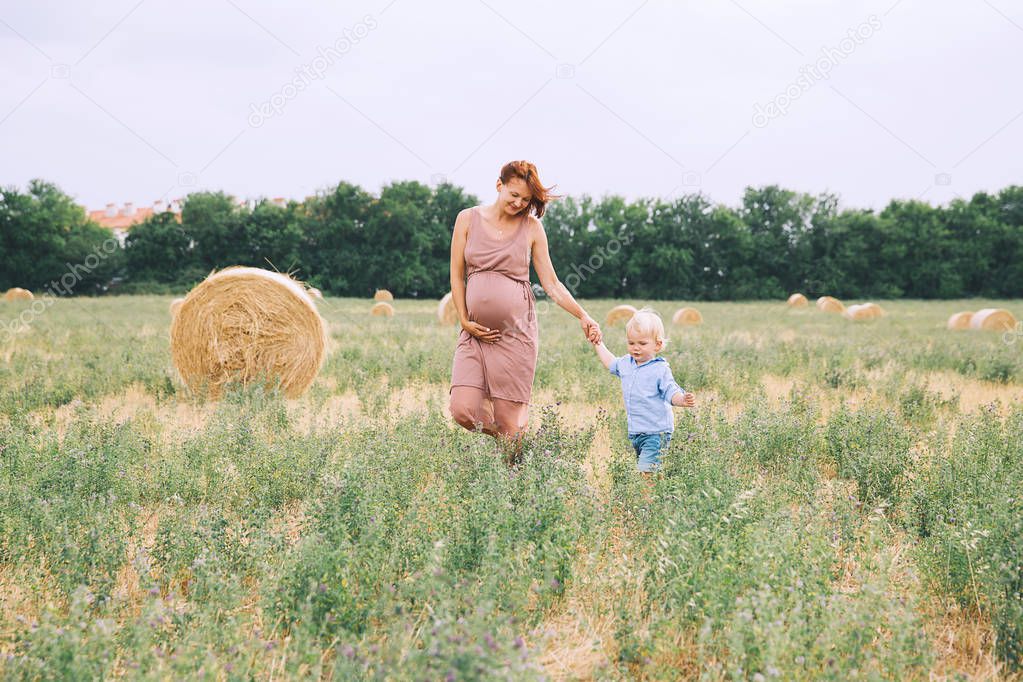 Pregnant woman and son on nature. 