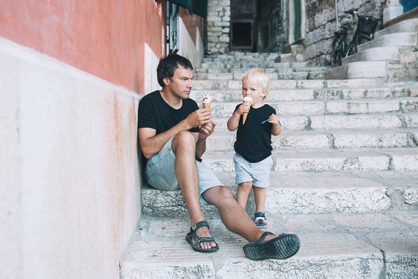 Pai e filho comendo juntos sorvete ao ar livre . — Fotografia de Stock