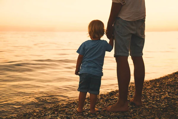 Padre e hijo atrás siluetas caminando por el mar . — Foto de Stock
