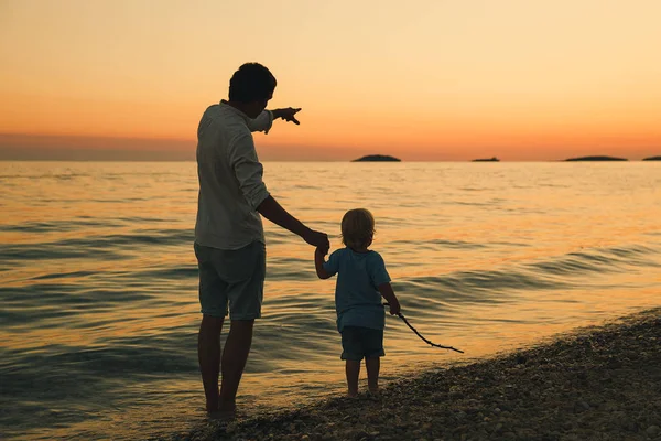 父と息子は浜辺の散歩シルエットをバックアップします。. — ストック写真