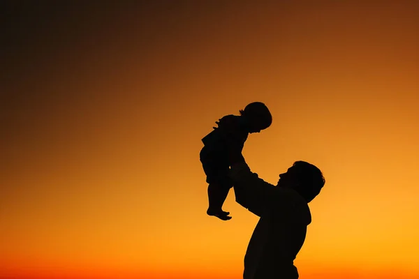 Vater und Sohn Silhouetten bei Sonnenuntergang am Strand. — Stockfoto