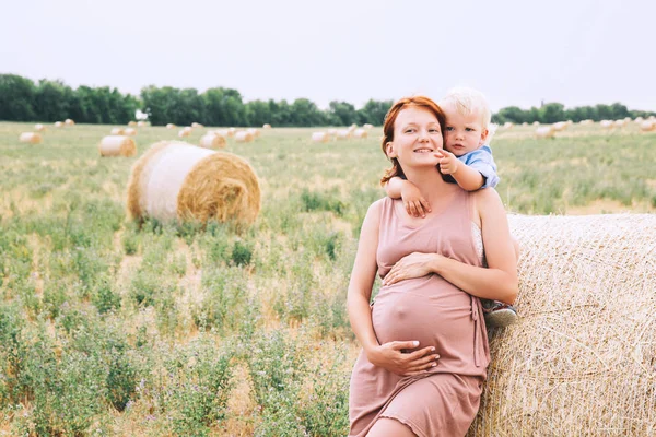 Femme enceinte et fils sur la nature. Mère attendant un deuxième bab — Photo