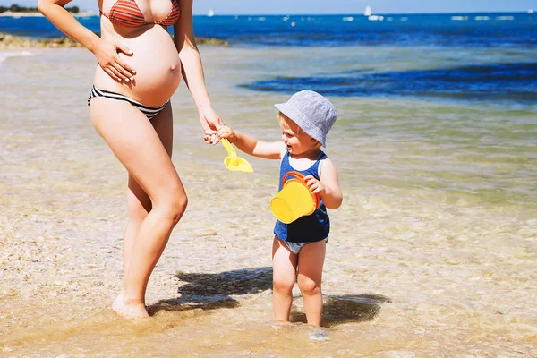 Schwangere Mutter und Kleinkind entspannen sich im Sommer am Strand — Stockfoto