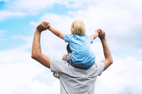 Vader en zoon met opgeheven armen tegen de hemel. — Stockfoto