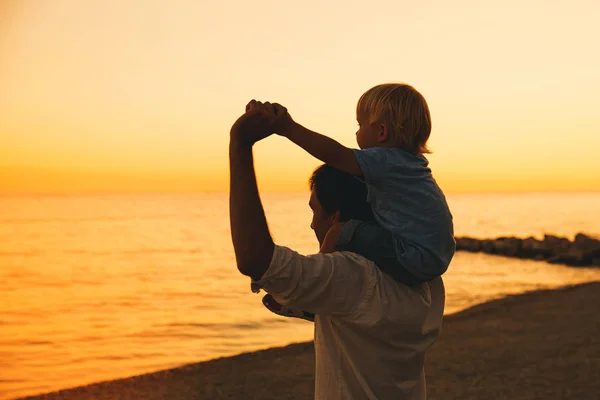 Силуэты отца и сына на закате на морском пляже . — стоковое фото
