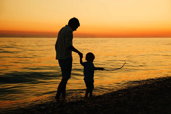 Father and son back silhouettes walking by the sea. — Stock Photo, Image