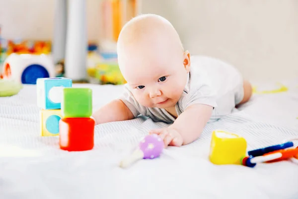 Bebê brincando com brinquedos coloridos em casa . — Fotografia de Stock