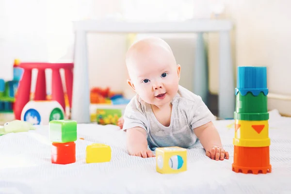 Baby spielt zu Hause mit buntem Spielzeug. — Stockfoto