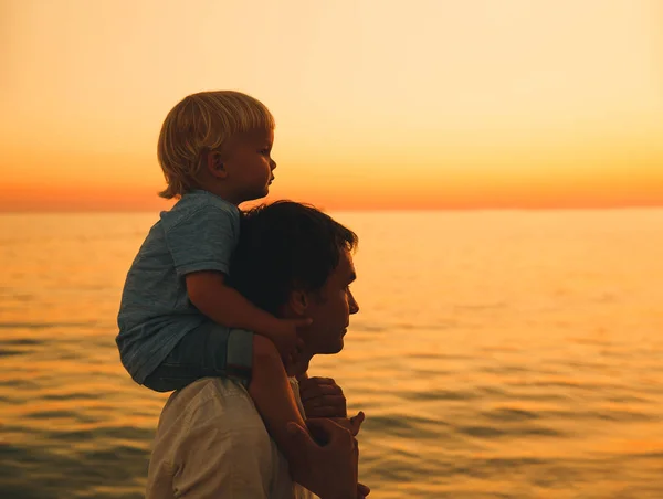 Силуэты отца и сына на закате на морском пляже . — стоковое фото