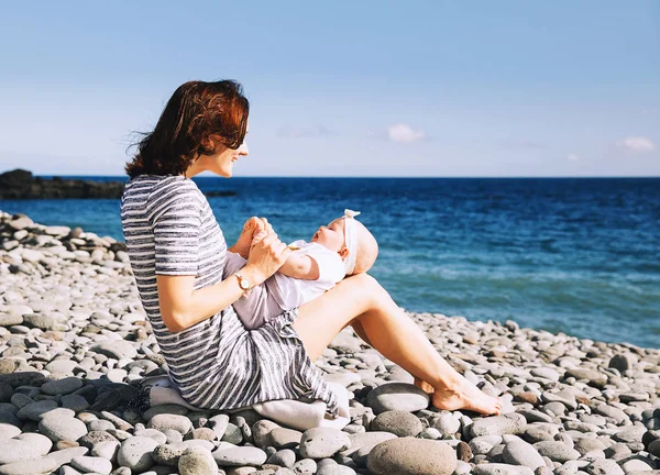 Mutter und Baby spielen draußen am Meeresstrand. — Stockfoto