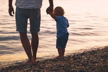 Baba ve oğul deniz tarafından yürüyüş siluetleri geri.