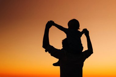 Gün batımında baba ve oğul siluetleri bir deniz plaj.